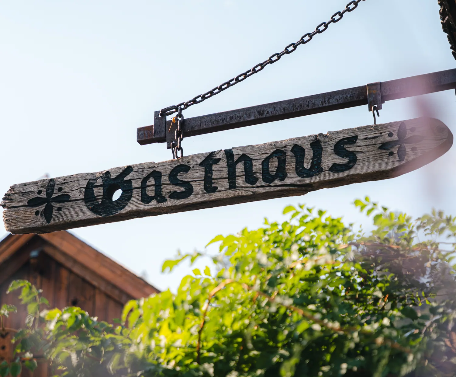 The rustic wooden Gasthaus sign hanging outside in the sunshine